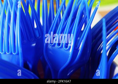 Nahaufnahme eines Bündels blauer Kunststoffgabeln stand in einem Plastikbecher auf, Zinken nach oben. Stockfoto