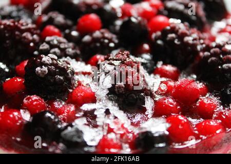 Nahaufnahme eines gefrorenen gemischten Beerenkäsekuchen mit einem leichten Eis und Frost auf den Beeren. Stockfoto