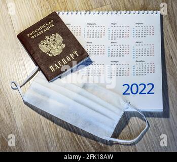 Russischer Reisepass und Kalender. Medizinische Maske und Kalender 2022. Sanitärmaske und Reisepass auf dem Tisch. Stockfoto