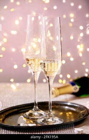 St. Valentine oder Hochzeit Grußkarte mit zwei Champagner Gläser auf Tablett stehen auf silbernen funkelnden Tisch, weiße Herzen, Bokeh Lichter. Festliche Tafel Stockfoto