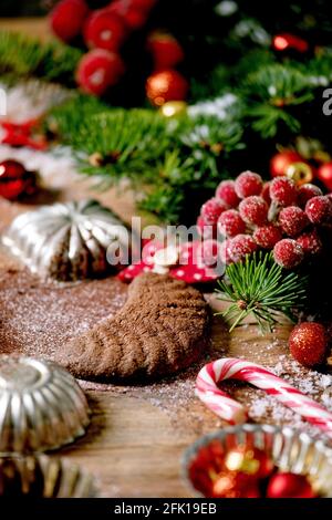 Hausgemachte traditionelle Weihnachten Mürbeteig Cookies Schokolade Crescents mit Kakao Puderzucker in Keramik-Platte mit Cookie-Formen, Tanne, rote Weihnachten st Stockfoto