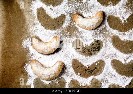 Hausgemachte traditionelle Weihnachten Mürbeteig Cookies Vanille Crescents mit Puderzucker auf Backpapier. Draufsicht Stockfoto