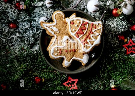 Hausgemachte traditionelle Weihnachten Lebkuchenkekse mit Verzierung verziert. Lebkuchenmann, Engel, Glocke auf Keramikplatte mit Weihnachtsschmuck und Tannenbaum Stockfoto