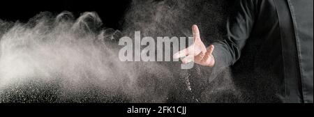 Die Hand des professionellen Kochs in einer Küche streut Mehl auf Ein Tisch zum Teigmachen Stockfoto