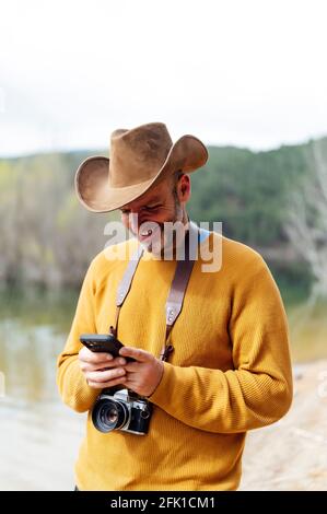 Lächelnder Mann, der auf das Telefon im Feld blickt Stockfoto