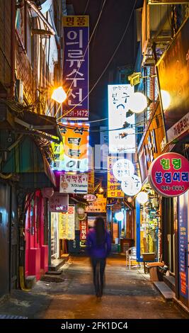 Frau, die durch die Hintergasse in Seoul läuft Stockfoto