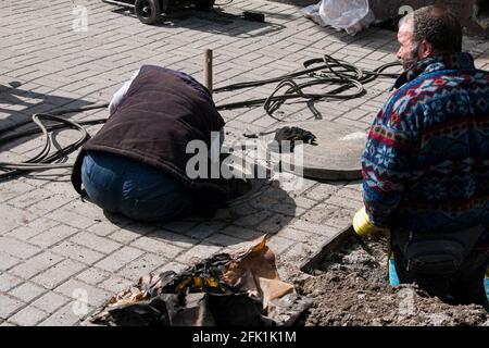 Dnepropetrovsk, Ukraine - 03.26.2021: Wasserversorger öffnen ein altes Kanalloch und ersetzen alte rostige Rohre durch neue. Stockfoto