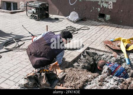 Dnepropetrovsk, Ukraine - 03.26.2021: Wasserversorger öffnen ein altes Kanalloch und ersetzen alte rostige Rohre durch neue. Stockfoto