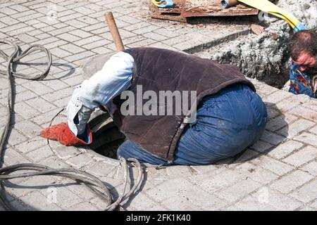 Dnepropetrovsk, Ukraine - 03.26.2021: Wasserversorger öffnen ein altes Kanalloch und ersetzen alte rostige Rohre durch neue. Stockfoto