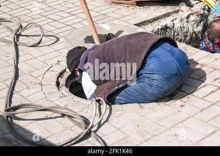 Dnepropetrovsk, Ukraine - 03.26.2021: Wasserversorger öffnen ein altes Kanalloch und ersetzen alte rostige Rohre durch neue. Stockfoto