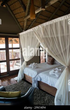 Moskitonetze bedecken Betten in einer luxuriösen Wüstenhütte in der Nähe der roten Sanddünen von Sossusvlei in der Nähe des Namib-Naukluft Parks, Namibia. Stockfoto