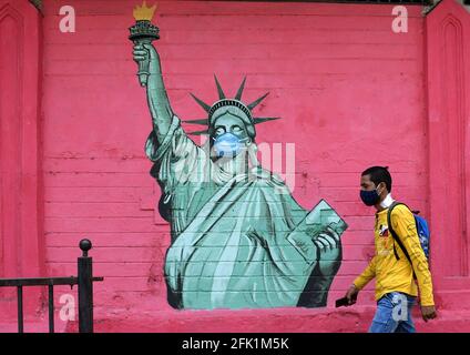 Mumbai, Indien. April 2021. Ein Mann mit einer schützenden Gesichtsmaske geht an einem Graffiti der Freiheitsstatue vorbei, das gemalt wurde, um Bewusstsein für die Corona-Virus-Krankheit in Mumbai zu schaffen.im Staat Maharashtra wird eine strenge Sperre auferlegt, um die Ausbreitung der Krankheit einzudämmen und die Situation schnell unter Kontrolle zu bringen. Kredit: SOPA Images Limited/Alamy Live Nachrichten Stockfoto