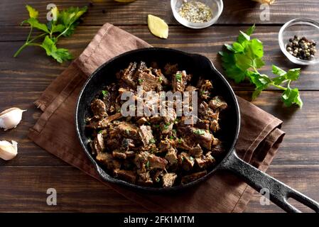 Nahaufnahme des langsam gekochten Pulled Beef in der Bratpfanne auf Holzhintergrund. Stockfoto