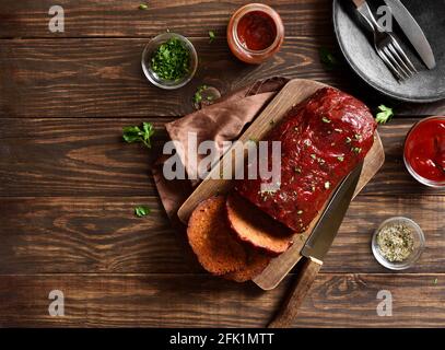 Hackbraten mit Glasur auf Schneidebrett auf Holzhintergrund. Draufsicht, flach liegend, Nahaufnahme Stockfoto