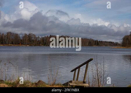 Schöner großer See in lettischen Wäldern mit wolkigen dramatischen gefunden Der Himmel spiegelt sich in ruhigem, sauberem Quellwasser Stockfoto