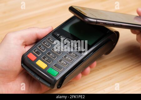 Kontaktloses Bezahlen mit dem Mobiltelefon über das drahtlose Zahlungsterminal Stockfoto