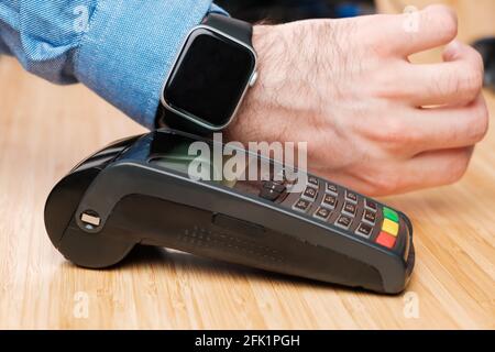 Kunden zahlen über die Smartwatch mit NFC-Technologie. Kontaktloser Zahlungsterminal. Stockfoto