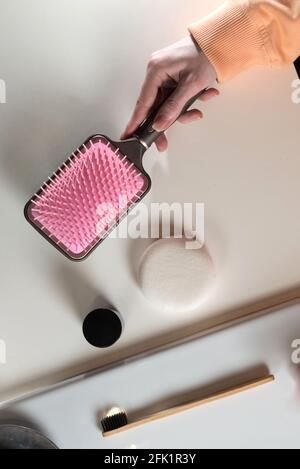 Draufsicht auf Badezimmerzubehör, Zahnbürste in der Nähe der Haarbürste, Bogen, Handy und Gesichtsschwamm auf einer weißen Oberfläche Stockfoto