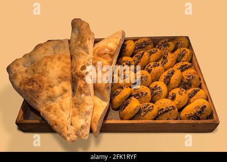 Focaccia-Brot und frisch gebackene Brötchen mit Oliven Pastete in Holzschale, isoliert auf beigem Hintergrund Stockfoto