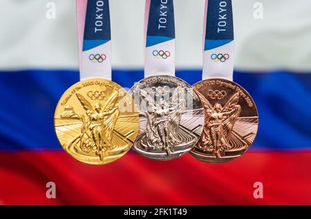 25. April 2021 Tokio, Japan. Gold-, Silber- und Bronzemedaillen der XXXII. Olympischen Sommerspiele 2020 in Tokio auf dem Hintergrund der russischen Flagge. Stockfoto