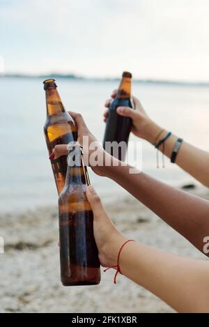 Eine Gruppe von Freunden trinkt Bier am Strand. Eine Gruppe von Freunden, die eine Sommerstrand-Party machen. Stockfoto
