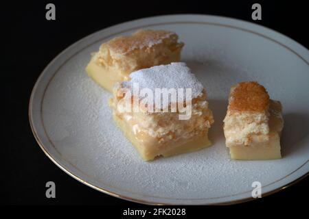 Hausgemachte frisch gebackene magische Torte; ein französisches Rezept namens 'gâteau magique' auf Französisch. Köstliches Dessert mit Granulat und Zucker auf dem Teller. Stockfoto