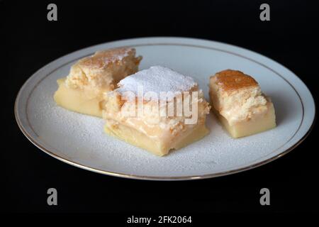 Hausgemachte frisch gebackene magische Torte; ein französisches Rezept namens 'gâteau magique' auf Französisch. Köstliches Dessert mit Granulat und Zucker auf dem Teller. Stockfoto