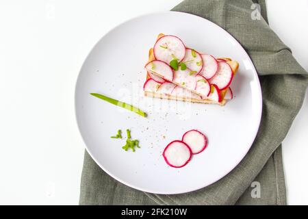 Gerösteter Toast mit frisch gehackten Radieschen und grünem Kraut auf dem weißen Teller. Gesundes Frühstück. Sandwich mit Gemüse. Stockfoto