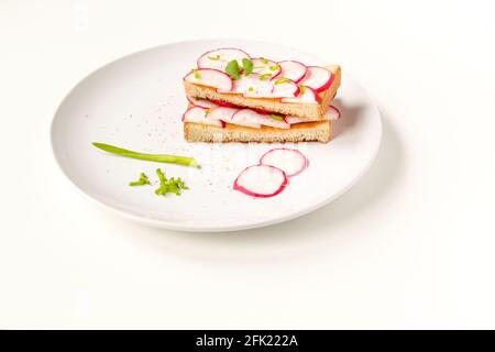 Gerösteter Toast mit frisch gehackten Radieschen und grünen Kräutern auf dem weißen Teller. Gesundes Frühstück. Sandwich mit Gemüse. Stockfoto