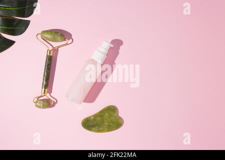 Jade Guasha Scraper Schröpfwalze Gesichtsmassager und kosmetische Creme. Das Konzept der Selbstversorgung. Keine Verschwendung. Hebe- und Tonungsbehandlung zu Hause. Stockfoto