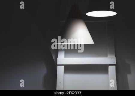 Abstrakter Innenhintergrund, Spotlichter und eine Holzleiter befinden sich in einem dunklen Raum Stockfoto