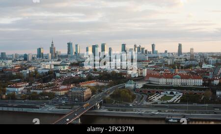 Luftaufnahme von Warschau, Hauptstadt von Polen. Skyline der Stadt mit wunderschönen Wolken im Hintergrund. Fahrzeuge, die auf der Brücke fahren. Vielbefahrene Straße. Die Aufnahme wird am Morgen gemacht. Wolkenkratzer berühren den Himmel. Stockfoto