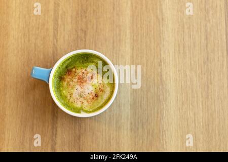 Blaue Tasse mit grünem Tee Matcha Latte, mit gefriergetrockneten Erdbeeren auf Holztisch, Platz zum Kopieren. Gesundes Ernährungskonzept, Getränke mit Gemüse oder Stockfoto