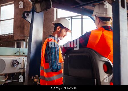 Glückliche Gabelstaplerfahrerin lächelt und schaut auf die Kamera Stockfoto