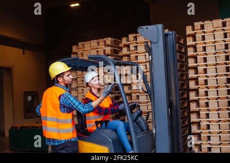 Glückliche Gabelstaplerfahrerin lächelt und schaut auf die Kamera Stockfoto