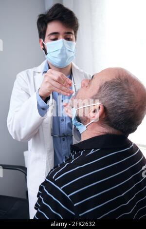 Reifer Mann, der während einer Coronavirus-Pandemie einen PCR-Test in der Arztpraxis erhält. Arzt mit Handschuhen und Maske beim nasalen Coronavirus-Test. Stockfoto