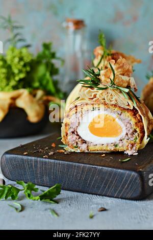 Scotch Eier in ein Pfannkuchen Tasche mit grünen auf einem grau-blauen Hintergrund. Ein klassisches Gericht in einer unkonventionellen dienen. Lecker und appetitlich Gericht von Brit Stockfoto