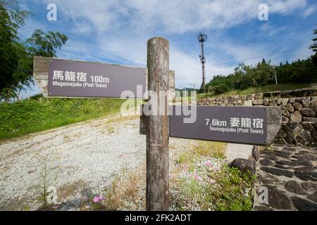 Wegweiser mit Wegbeschreibung und Entfernung nach Magome nach Tsumago. Nakasendo Trail Berglandschaft. Wanderung durch das japanische Kiso-Tal, Japan. Stockfoto