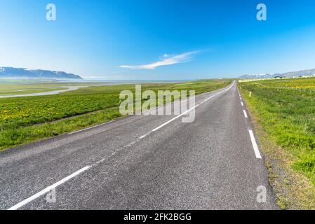 Verlassene gerade Straße entlang der Aue in der Nähe der Küste von nordisland an einem klaren Sommertag Stockfoto