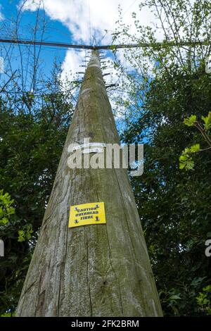 Ländliche Breitbandnetze, die durch ein „Vorsicht-Overhead-Glasfaserschild“ auf der Seite des britischen Suffolk veranschaulicht werden. Stockfoto