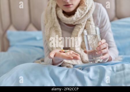 Weibliche Einnahme von Pillen, Kapseln mit Glas Wasser, zu Hause im Bett Stockfoto