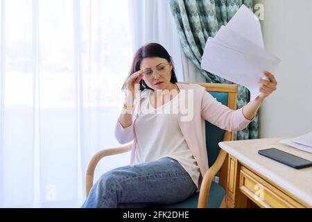 Reife Frau winkt Papiere, leidet an Hitze Stockfoto