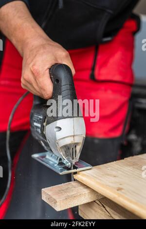 Nahaufnahme eines unbekannten Zimmermanns, der mit einem arbeitet Elektrische Stichsäge Holz schneiden mit Säge Holzbearbeitung Hobby Konzeptkopie Platz Stockfoto