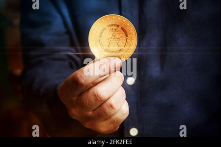 Cardano Ada Kryptowährung Symbol goldene Münze in der Hand abstraktes Konzept. Stockfoto