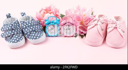 Mädchen und Jungen Schuhe mit rosa und blauen Uhren auf rosa Hintergrund. Baby Geburtstag, Einladung oder Grußkarte mockup. Banner. Speicherplatz kopieren. Stockfoto