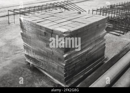 Betonblöcke in Zellophanfolie auf einer Baustelle verpackt. Betonsteine in einem Industriegebiet. Lagerung von Pflastersteinen im Lager Stockfoto