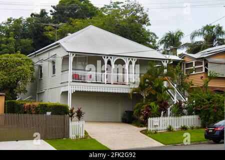 Weißes queenslander Haus mit tropischem Grün und hohen Bäumen Bewölktes Wetter in Australien Stockfoto