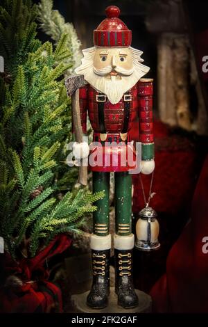 Holzschnitzler Weihnachtsnutcracker mit Axt und Latern umgeben von Bäume und Holz und rotes Karloid Stockfoto