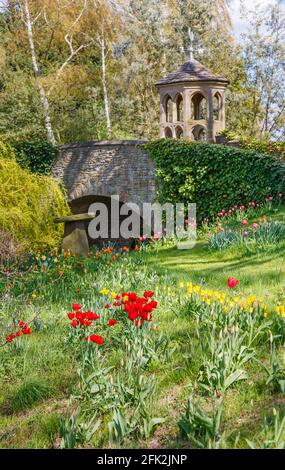 Farbenfrohe rote und gelbe Tulpen, Torheit und Steinbrücke beim Frühlingsfest im Dunsborough Park, Ripley, Surrey, Südostengland im April Stockfoto