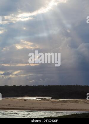 Sonnenschein strahlt seine Strahlen durch die Wolken über dem Strand Stockfoto